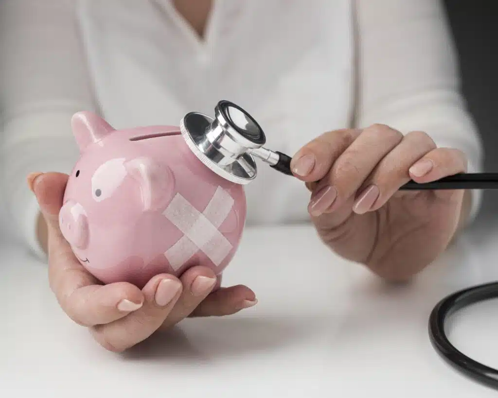 person-putting-stethoscope-piggy-bank