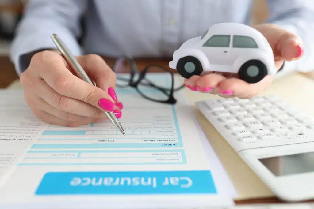 woman-holding-toy-car-her-hands-filling-out-insurance-form-closeup