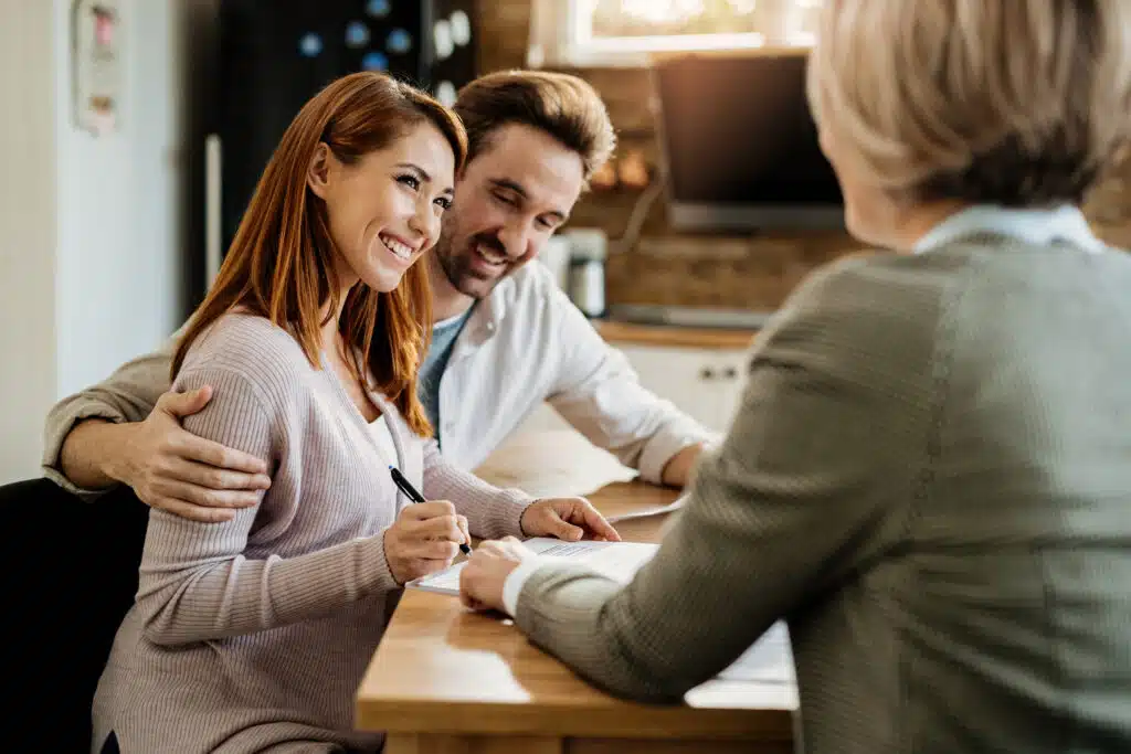 Happy couple signing a contract during a meeting with financial advisor.